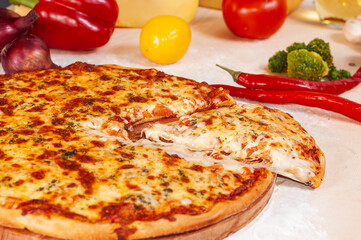 slice is cut from a fresh round pizza. Head of cheese and vegetables in the background.