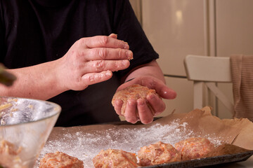 a man molds chicken meatballs and puts them on a baking tray, close up