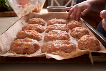 a man molds chicken meatballs and puts them on a baking tray, close up
