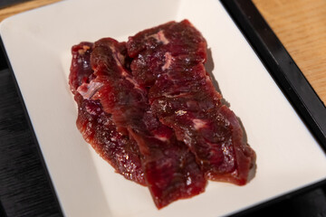 Korean Style Barbecue on plate in front of stainless grill. BBQ rare meat
