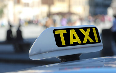 Yellow TAXI text waiting for passengers with blurred city background