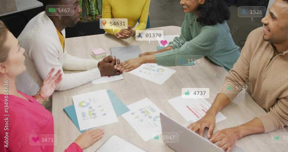 Aufkleber collaborating at table, diverse team using animation with social media icons overlay