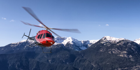 Red Helicopter Flying Over Canadian Mountain Landscape in Clear Blue Sky © edb3_16