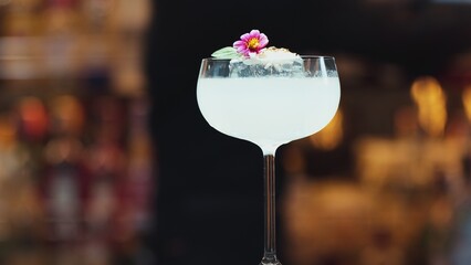 Closeup hand bartender using strainer in vodka coconut smooth fizzy cocktail at luxurious counter...