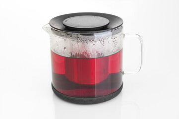 Glass teapot with hot tea close up on a white background