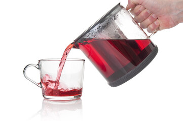 Hand pouring fresh tea from glass teapot on white background
