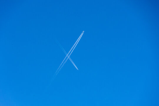 Contrail crossing in clear blue sky with airplane, March 2025