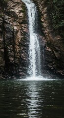 Obraz premium Serene Waterfall Cascading Down Rocky Cliffs into a Deep Pool of Water