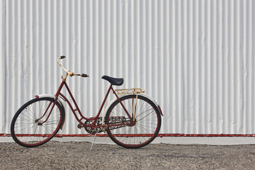 Old red rusty bike in front of white metallic wall. Iceland