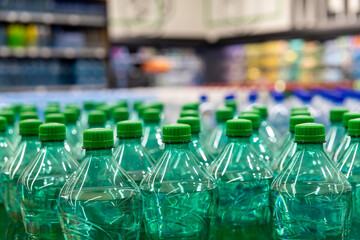  Green plastic water bottles neatly arranged in supermarket aisle with colorful blurred background