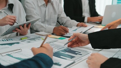 A diverse team engages in a collaborative business meeting, surrounded by charts and digital...