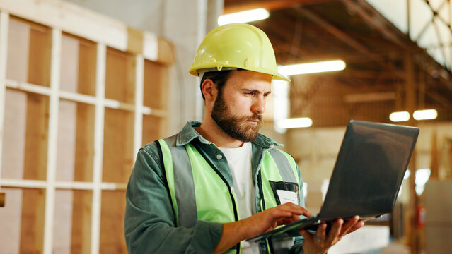 Engineer, man and carpenter with laptop for construction, manufacturing or furniture production. Person, carpentry and computer in factory for building, woodwork design or serious for problem solving