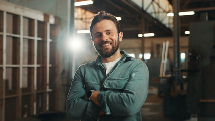 Obraz premium Portrait, carpenter and man with arms crossed, business and confident for career growth in warehouse. Manufacturing, entrepreneur and person with smile for startup, production and wooden furniture