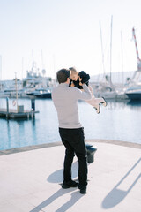 Dad spins a laughing little girl in his arms while standing on the boardwalk. Back view