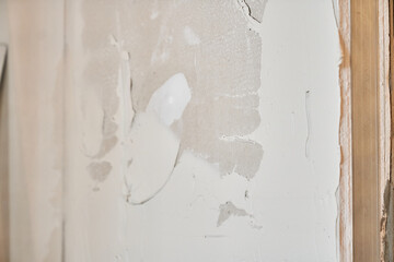 Putty stains on the wall. Textured white putty or plaster close-up on the wall, creating a smooth...