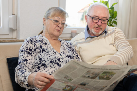 An elderly couple discussing news from a newspaper. They are gesturing and discussing the latest news. The boring life of a pensioner
