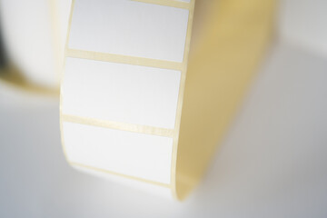 Curled roll of blank adhesive labels .Blank adhesive label roll with yellow border . Close-up of a...