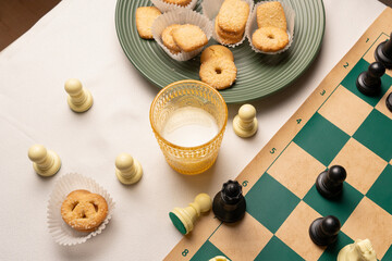 Enjoying chess and cookies with milk on a table