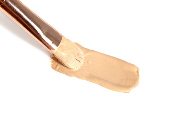 Foundation cream smeared with a brush on a white background.