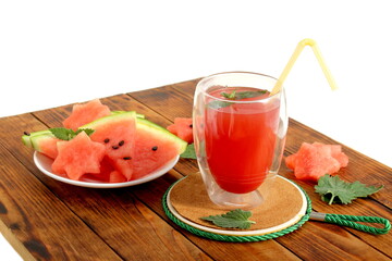 There is a glass with watermelon juice on the wooden table.