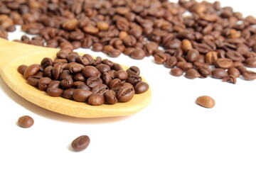 On a white background lies a wooden spoon with coffee beans.