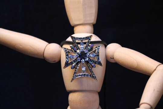 Figure of a wooden man with a brooch with precious stones 