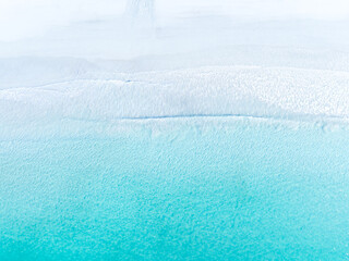 Drone view of white sand beach and azure sea. Water on the sea coast. Summer vacation and holiday. Transparent sea water and waves. Photography for background, postcards, wallpapers.