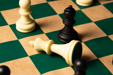 Black pawn defeats white king on green chessboard