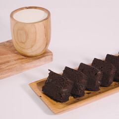 Chocolate brownies on a wooden tray ready to be served with a glass of fresh milk