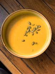 Creamy Pumpkin Soup with Seeds on Wooden Table, top view.
