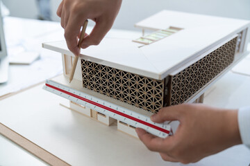 Closeup of professional architect hand measuring house model by using ruler and architectural...