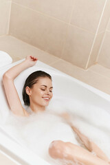 Relaxed woman enjoying a bubble bath, smiling contentedly, surrounded by soft foam and a serene...