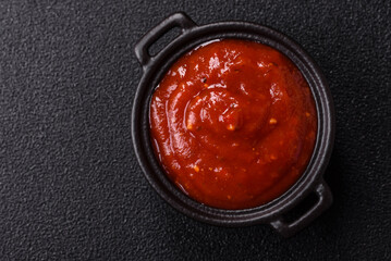 Red sauce or ketchup with salt and spices in ceramic sauce boat