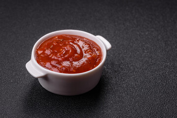 Red sauce or ketchup with salt and spices in ceramic sauce boat
