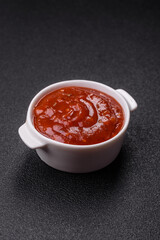 Red sauce or ketchup with salt and spices in ceramic sauce boat