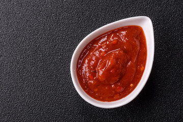 Red sauce or ketchup with salt and spices in ceramic sauce boat