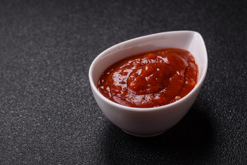 Red sauce or ketchup with salt and spices in ceramic sauce boat
