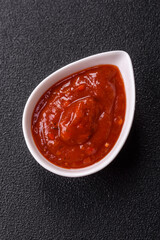 Red sauce or ketchup with salt and spices in ceramic sauce boat