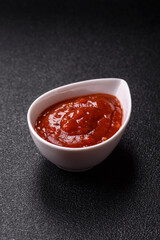 Red sauce or ketchup with salt and spices in ceramic sauce boat