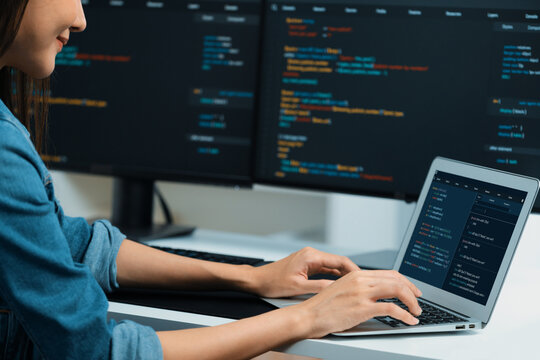 Smiling young Asian in IT developer creating with typing online information on laptop with coding program data of application, wearing jeans shirt. surrounded by safety analysis two screen. Stratagem.