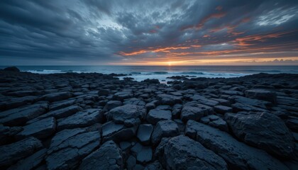 Dramatic Sunset Over Rocky Shoreline with Dark Clouds and Waves
