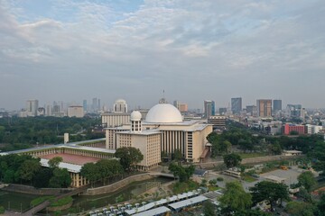 Aerial view of Istiqlal Mosque. It is the largest mosque in Southeast Asia and noise cloud with Jakarta cityscape. JAKARTA - Indonesia. May 16, 2021