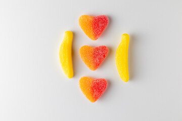 Banana and heart shaped candy forming a pattern on white background