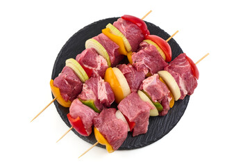 Raw meat skewers with vegetables isolated on white background.