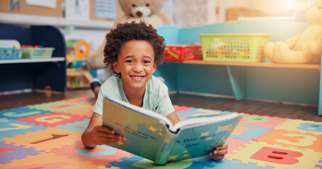 Boy, reading book and portrait on floor in home for development, story and knowledge in morning....
