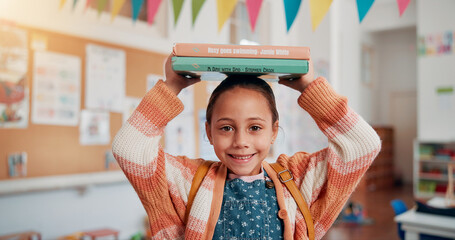 Girl, smile and books on head in classroom, portrait and excited for education, story or development. Child, happy and learning at academy, study and scholarship with reading at school in Mexico