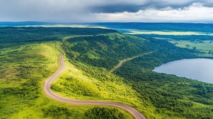Winding scenic road through lush green landscape near serene lake on cloudy day