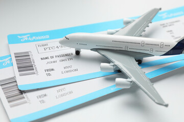 Travel agency. Flight tickets and plane model on light background, closeup