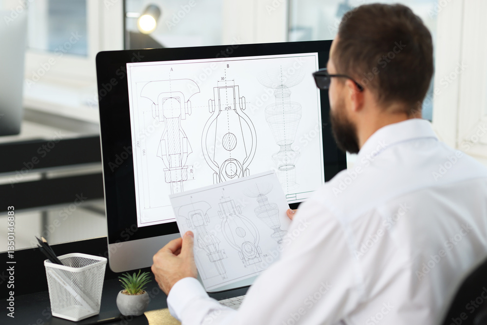 Poster technician making digital engineering drawing on computer at desk in office, back view