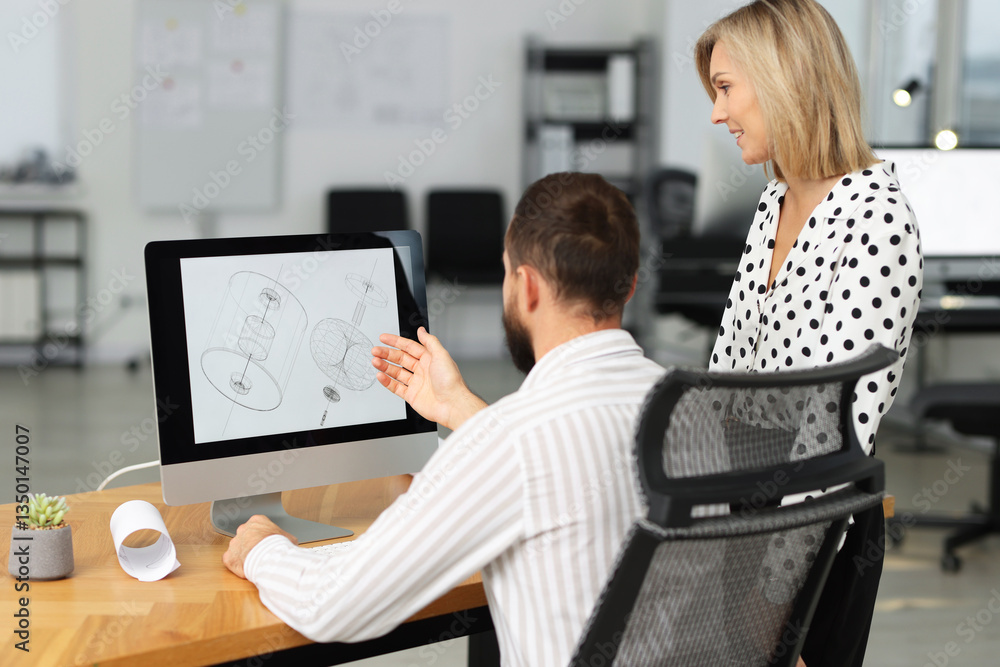 Poster technicians making digital engineering drawing on computer at desk in office